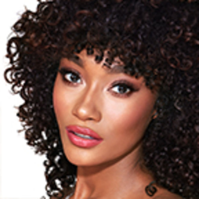 The Supermodel look on deep-tone model A deep-tone model with brown eyes wearing shimmery rose gold and brown eye makeup with brown eyeliner, soft pink blush, and magenta lipstick with gloss on top.