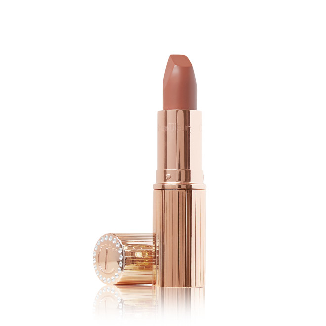 An open matte lipstick in a warm, peachy-nude shade with its lid next to it.
