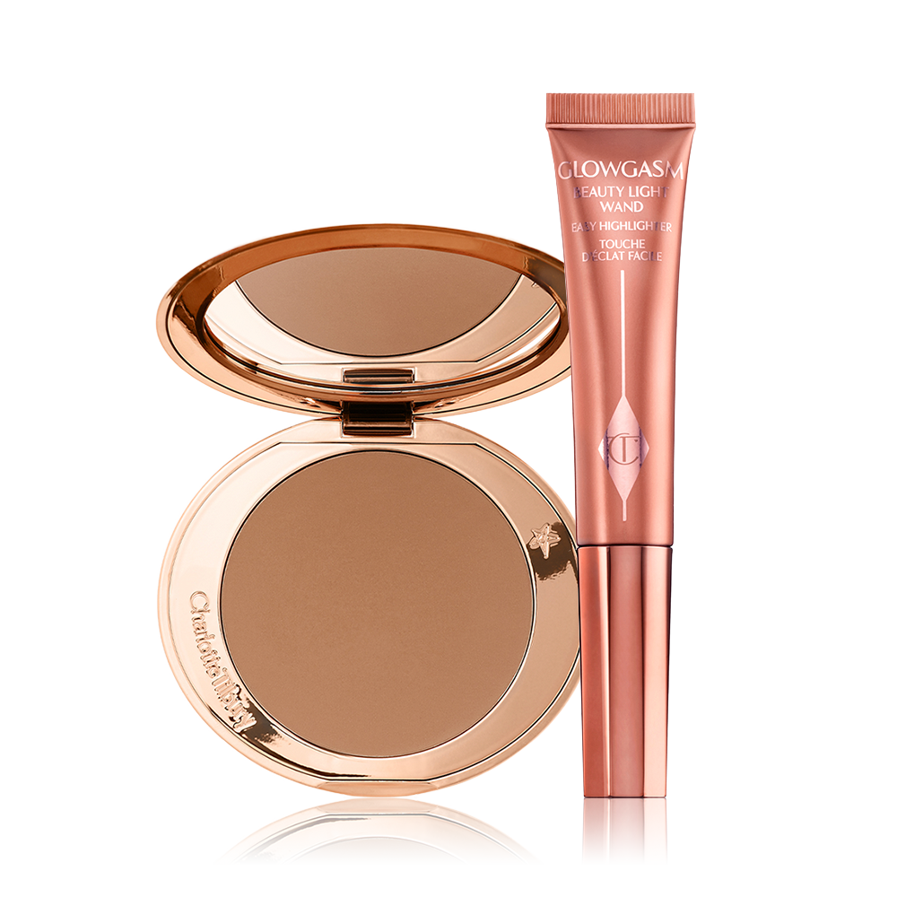 Airbrush Bronzer and Beauty Light Wand displayed An open, mirrored-lid bonzer compact with a warm-brown bronzer and a highlighter-blush wand in a warm pink shade.