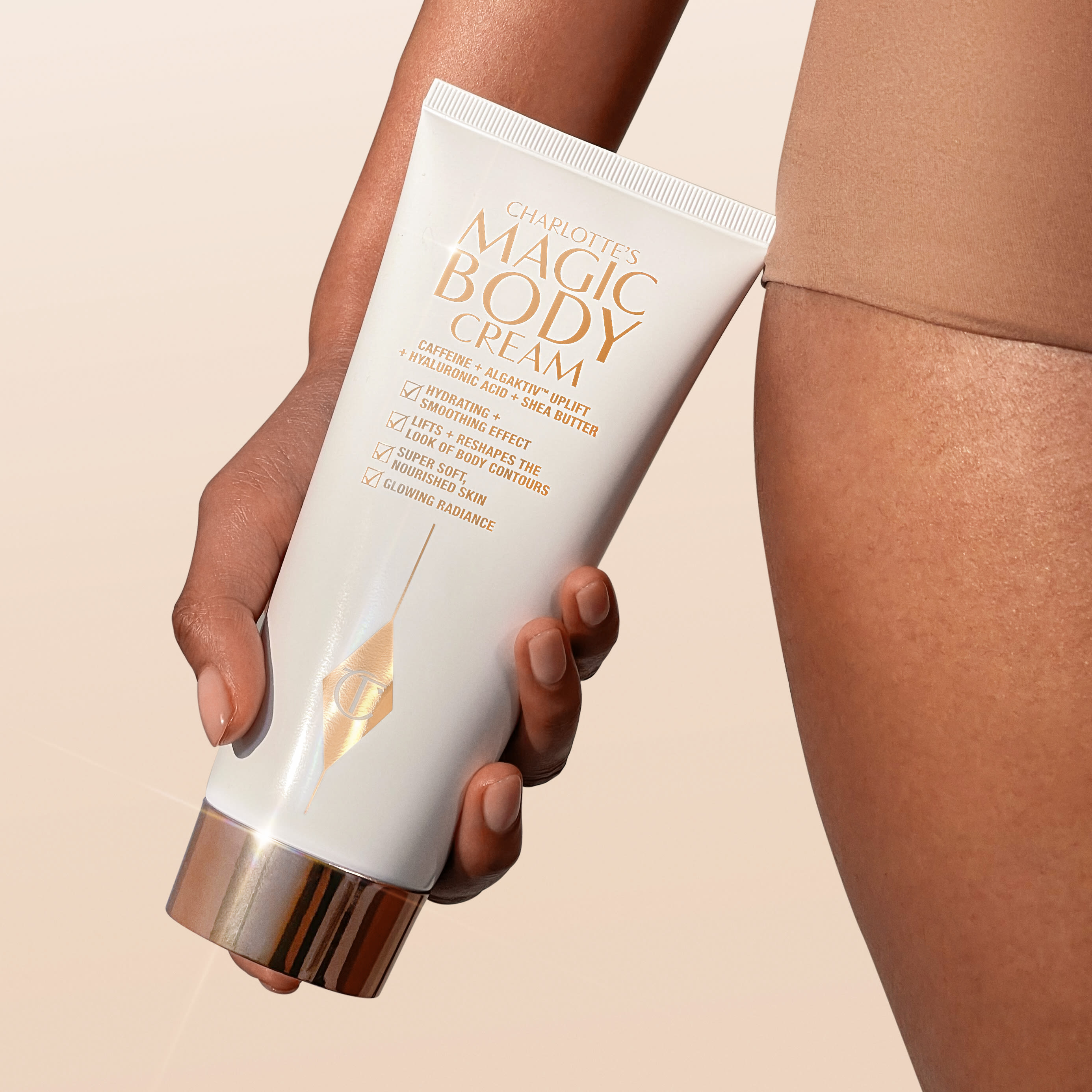 Magic Body Cream model shot Model holding Charlotte's Magic Body Cream for smoother, firmer-looking skin
