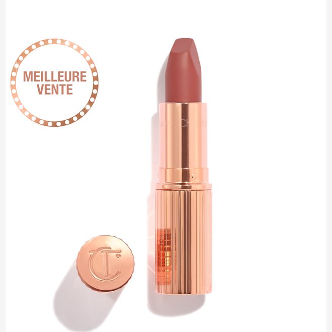 Rouge à lèvres Matte Revolution en Pillow Talk Medium avec la capuchon retiré Ouvert, le rouge à lèvres rose framboise se trouve dans un étui métallique et doré avec son couvercle embossé des lettres CT placé à côté.