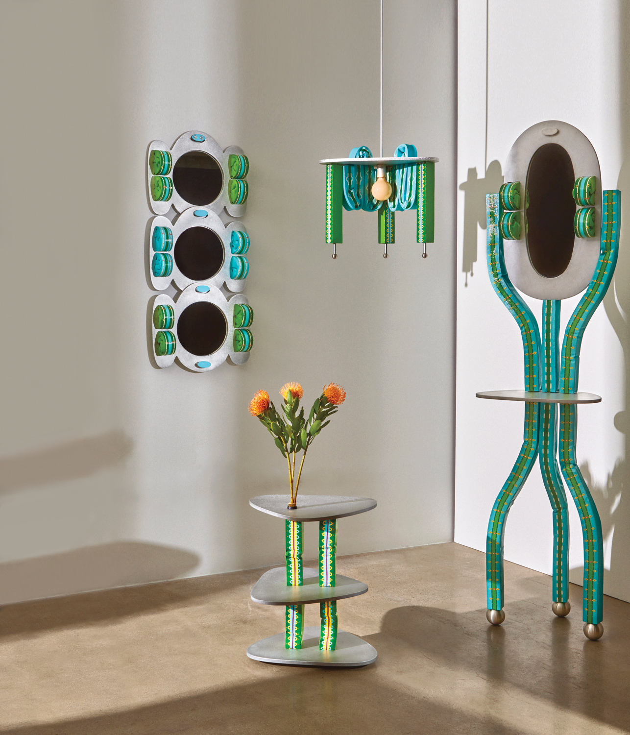 A three-tiered side table, three-piece wall mirror, pendant light and a standing mirror on display