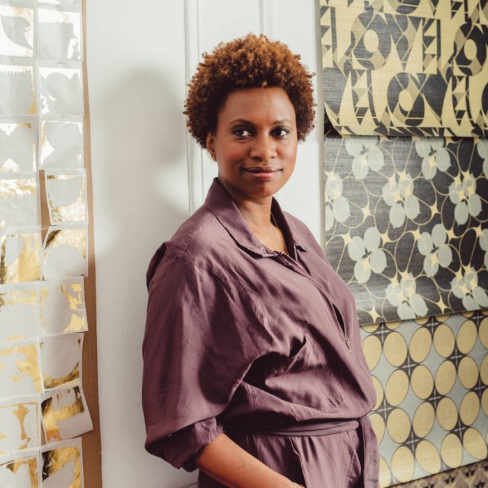 Artist Lisa Hunt stands in her Brooklyn studio next to gold leaf sheets that she will use in new work and grasscloth wallpaper samples.