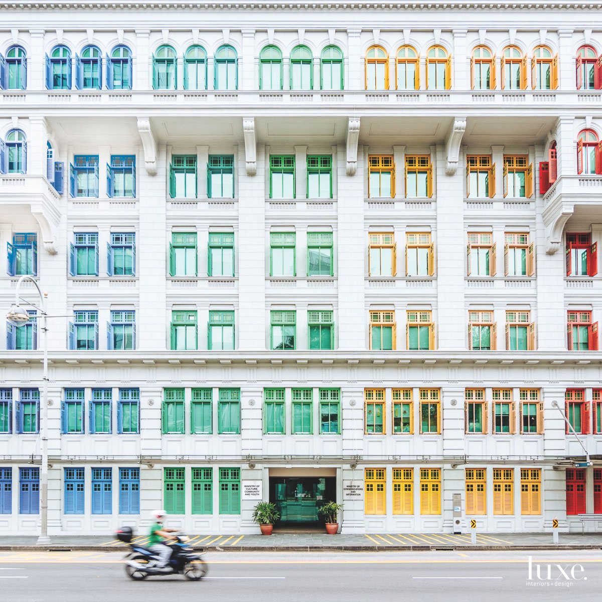 A virtual rainbow colors the window trim and shutters on the facade of a historic Singapore building in this photo by Marc Nouss.