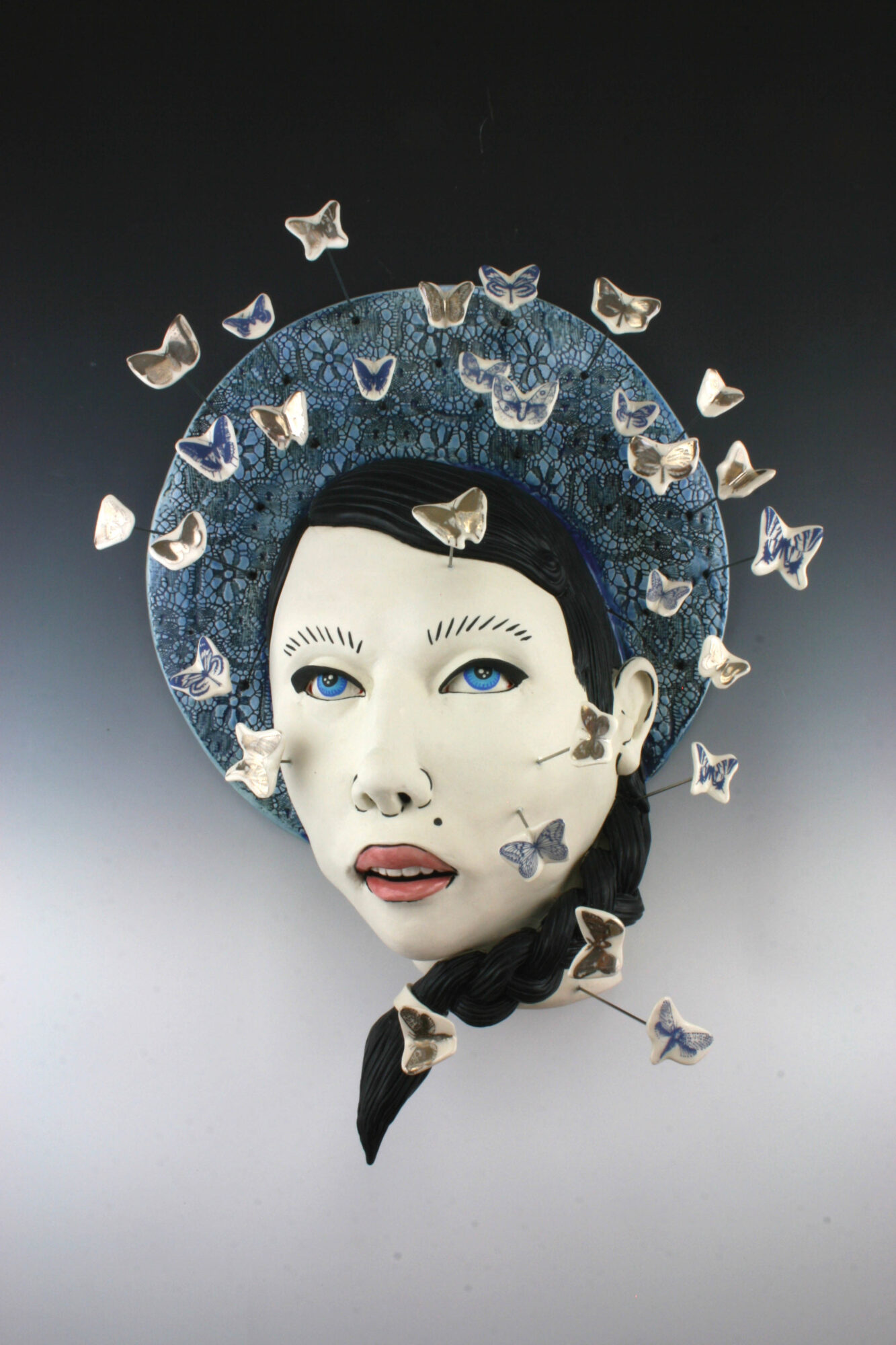 Ceramic artwork of woman's face and butterflies