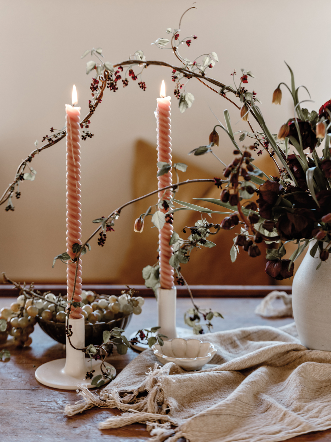 Tablescape with tall candles and greenery in a white vase.