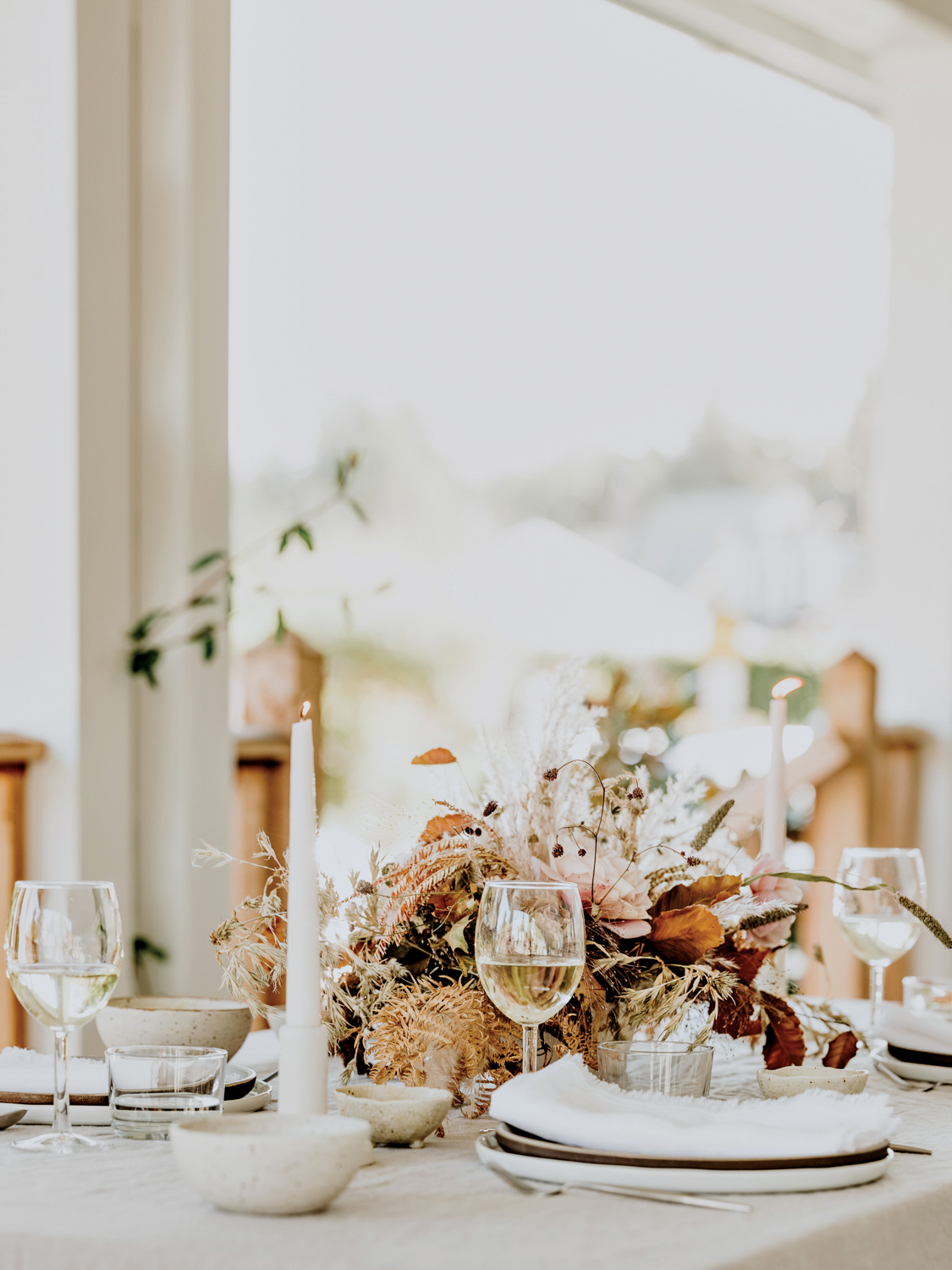 Tablescape with white candles and dried floral centerpieces.