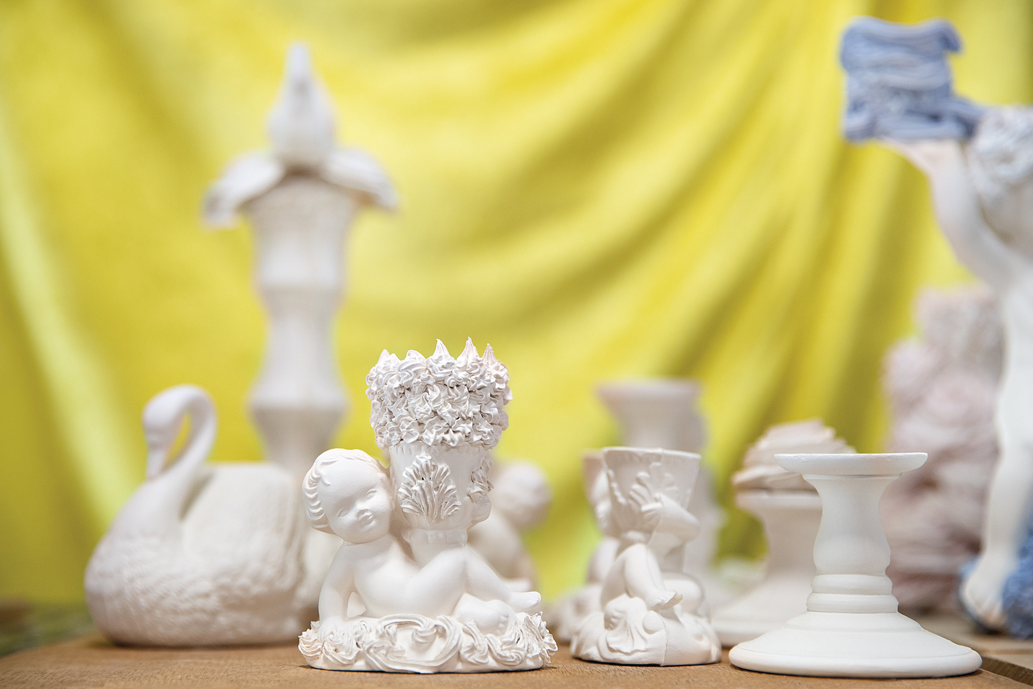Porcelain cherub candlesticks with yellow background
