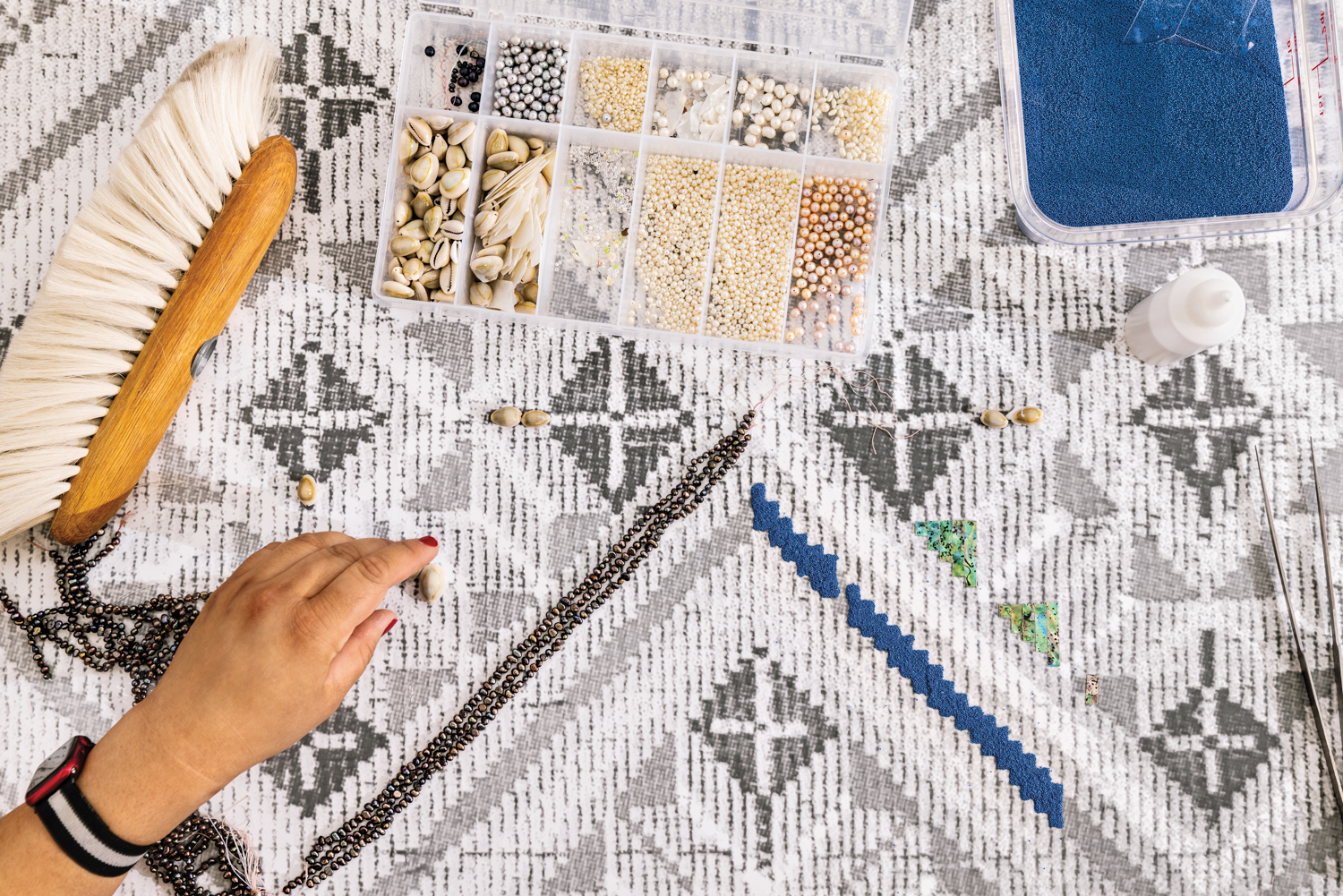 The artist adds small beads to a canvas.