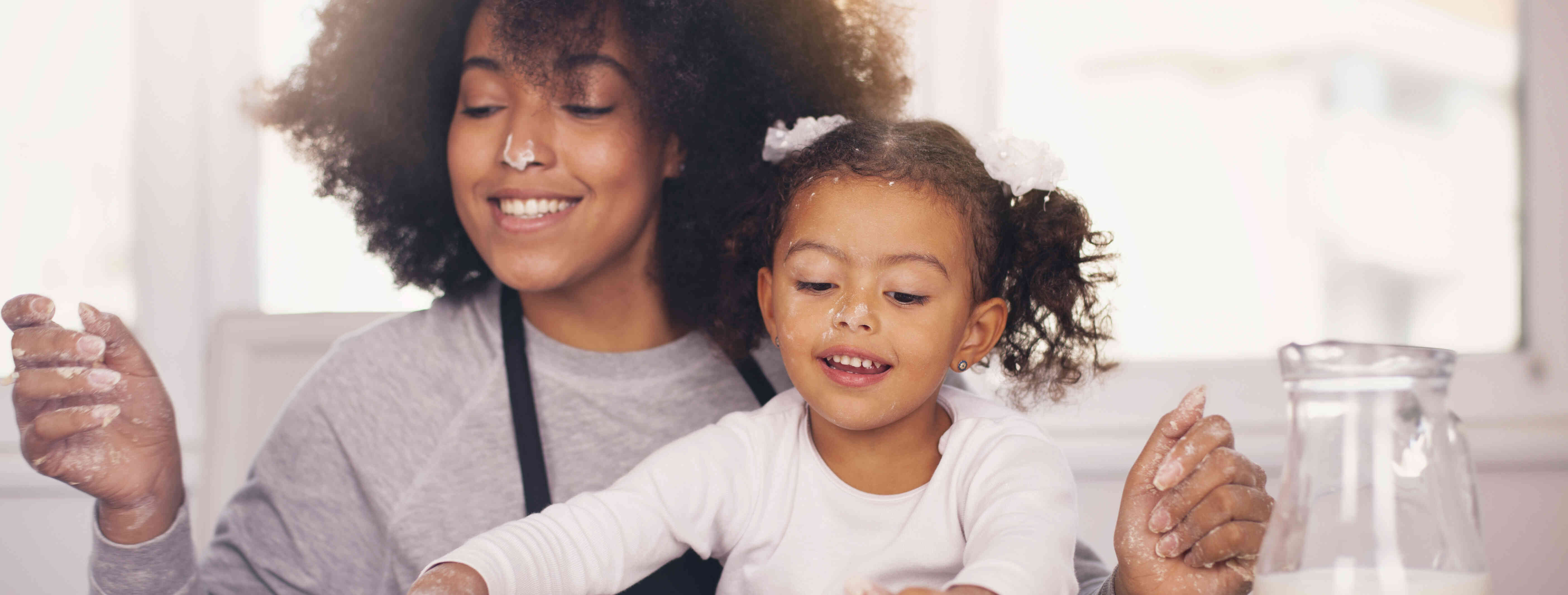 child care provider and girl cooking together in the kitchen