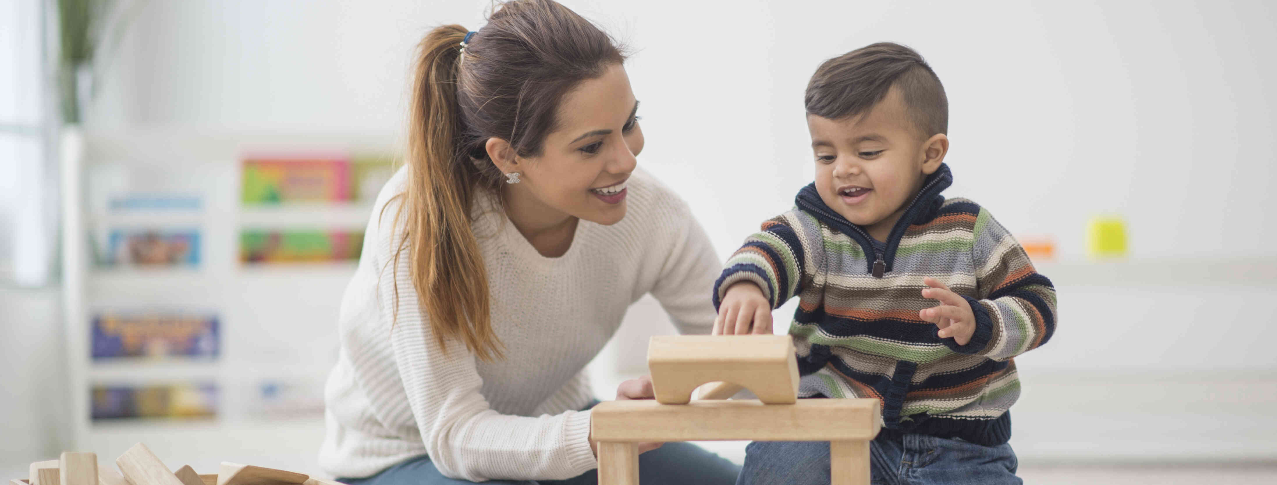 babysitter helping child with a puzzle.