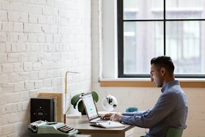 man-sitting-on-green-chair-while-using-laptop-374831