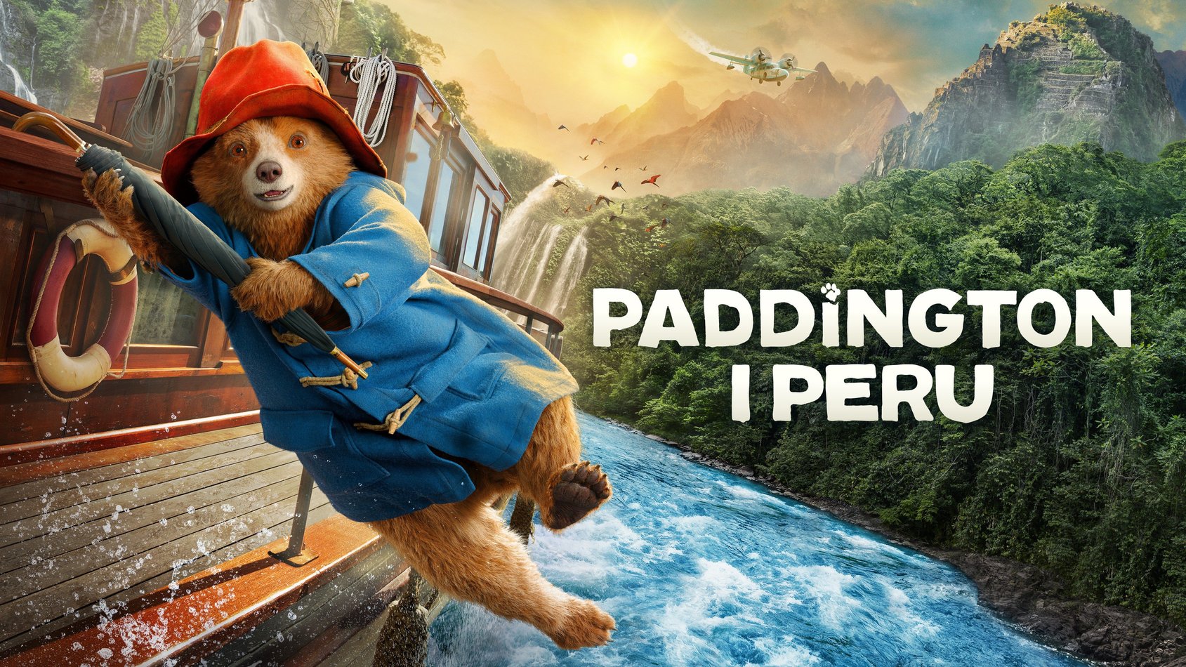 Paddington-björnen i blå kappa och röd hatt hänger på en båt över en flod med peruansk djungel i bakgrunden.