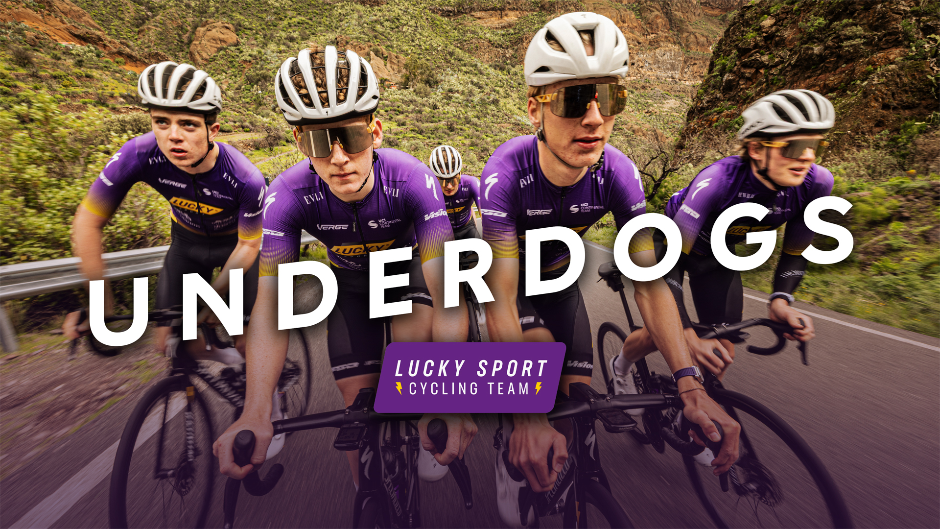 Lucky Sport Cycling Team cyklar i lila dräkter på en bergsväg med texten "Underdogs" i förgrunden.