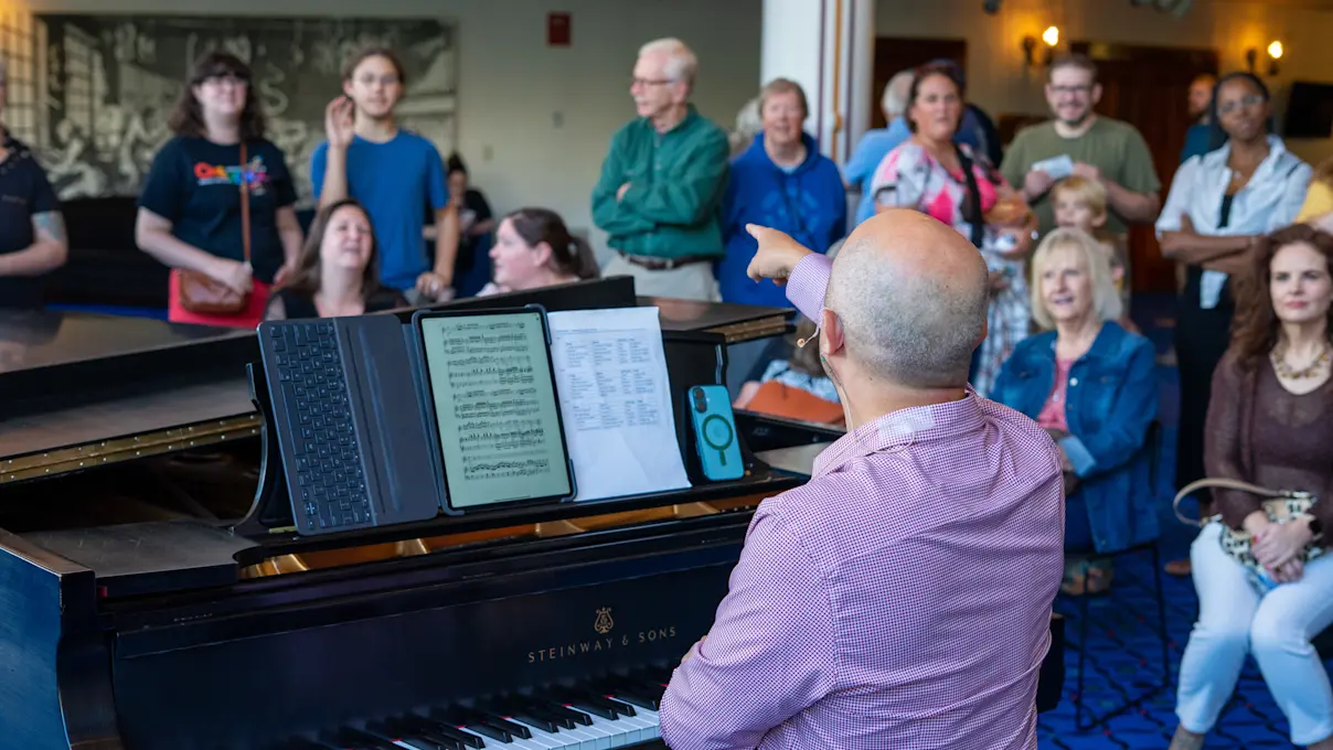Guests gathered around a piano at the 40th Anniversary Open House. Photo by Imani Mansfield.