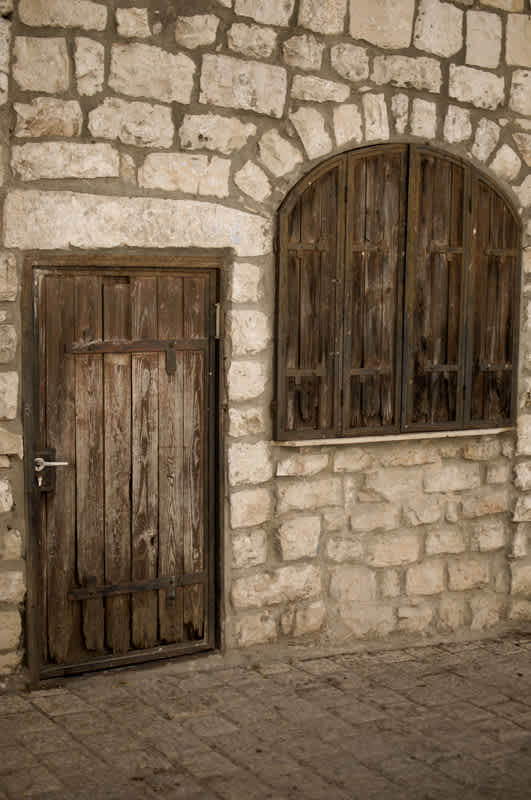 Small wooden door and window in a stone wall in Tzfat, Israel.