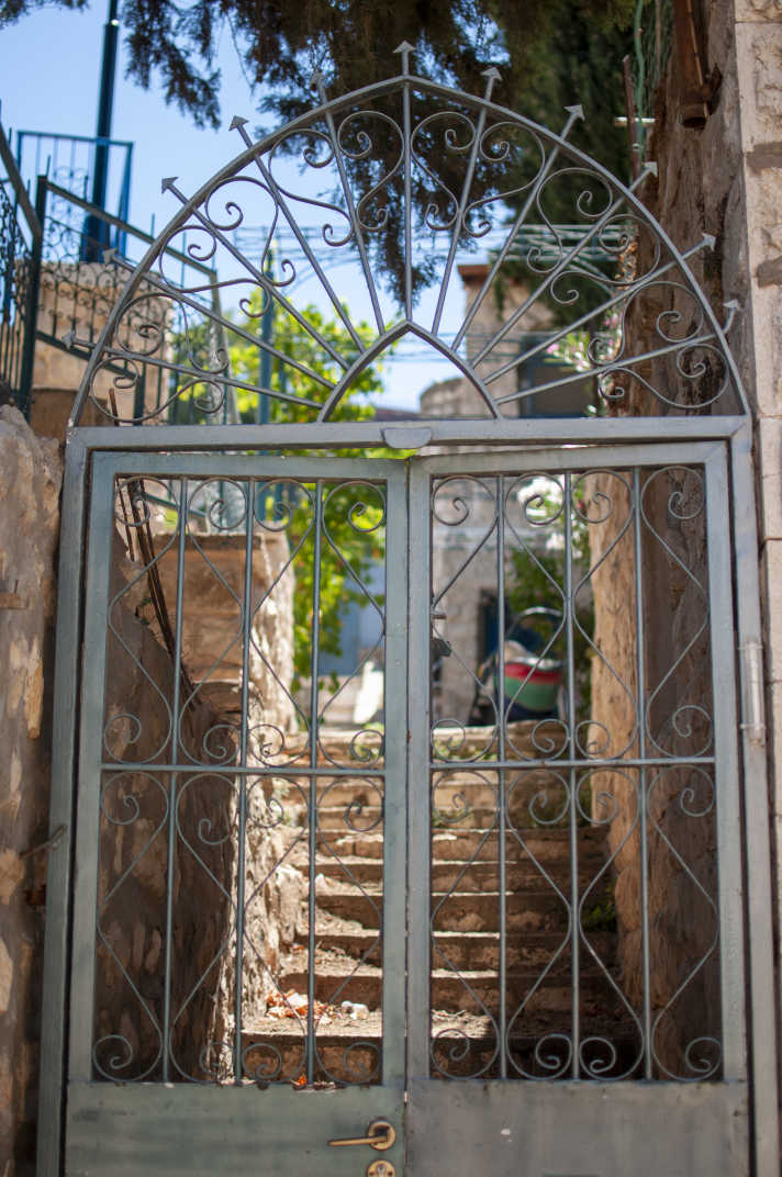 Fancy black metal gate blocks stairs leading up an alley way in Tzfat, Israel