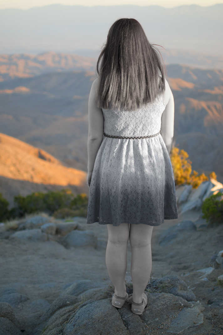 Black and white girl in facing colored mountain scenery.  