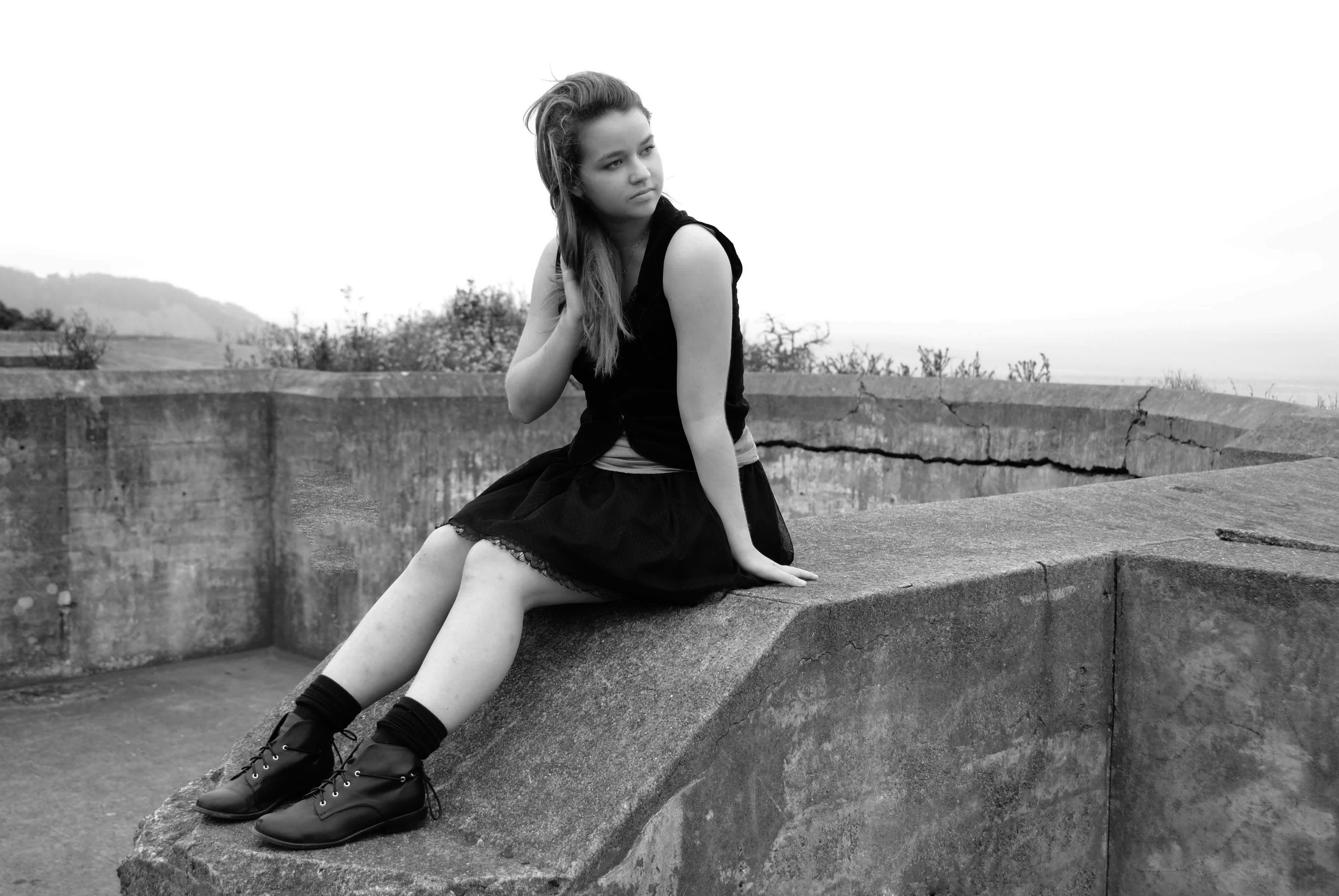 Black and white girl sitting on a wall. 