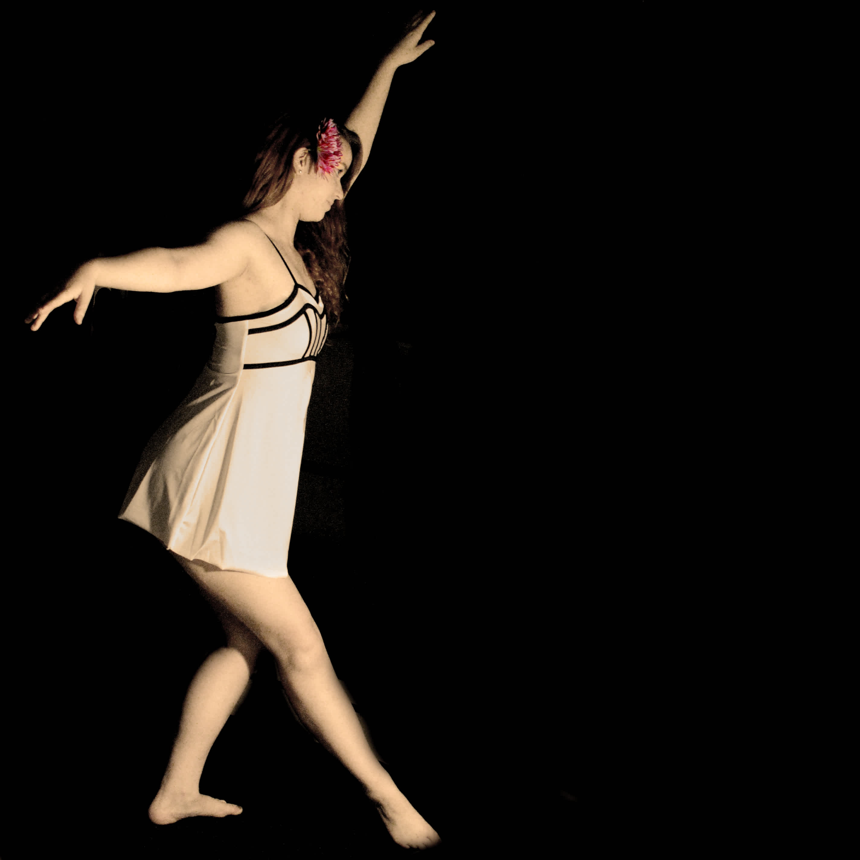 Girl dancing in front of a black background. 