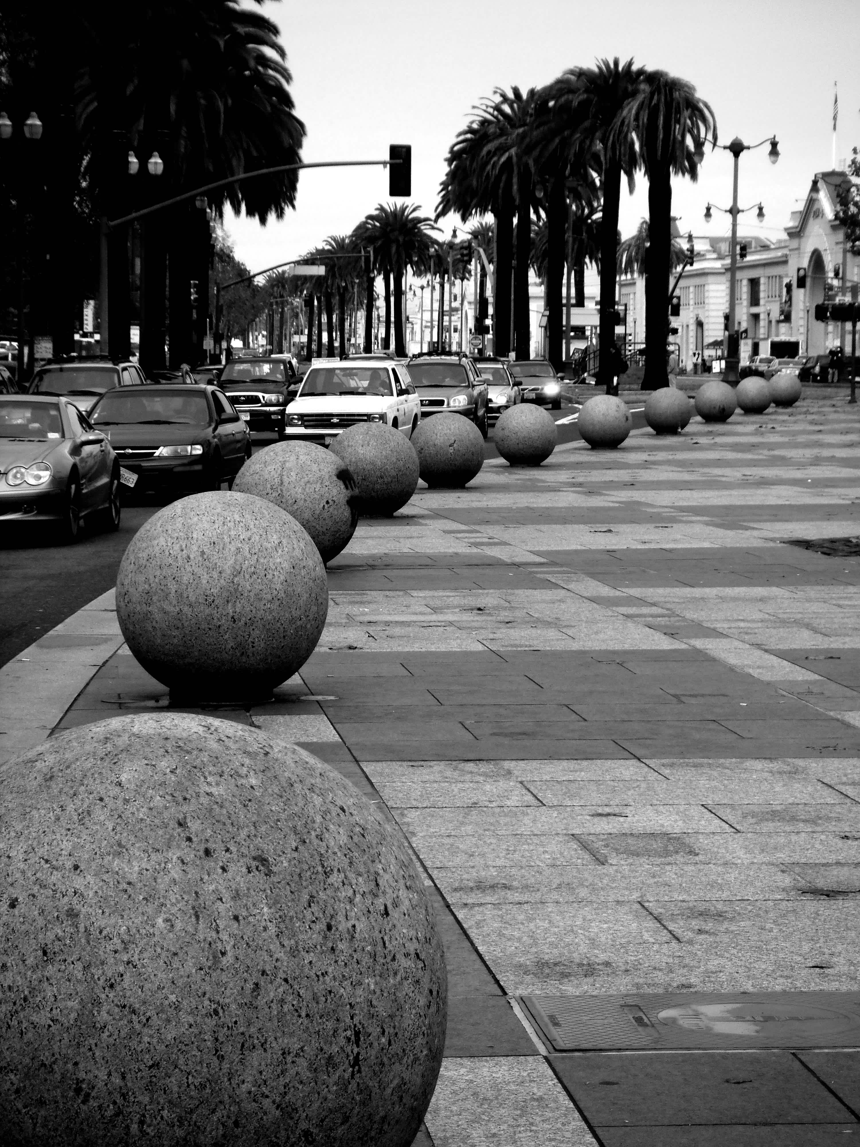 Marble orbs decorating the sidewalk with a cityscape background in black and white in Embarcadero, San Francisco, California.