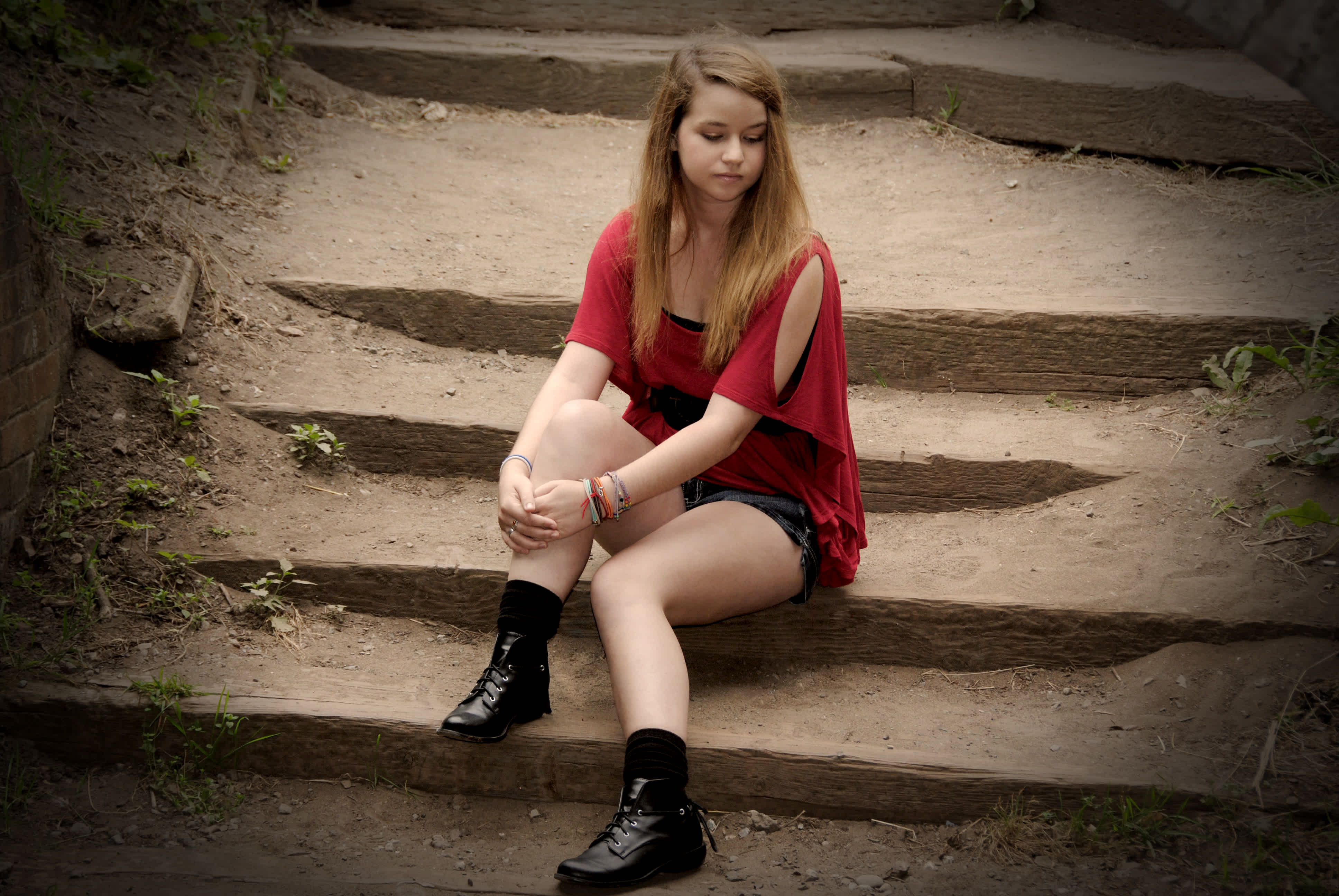Girl sitting on dirt-covered stair steps. 