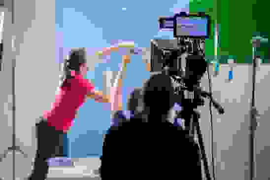 woman in a pink long-sleeve shirt holding a toothpaste and showing it on a video camera