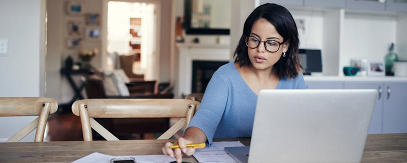 Feature image - Spousal support Young woman using a laptop and calculator while working on kitchen table
