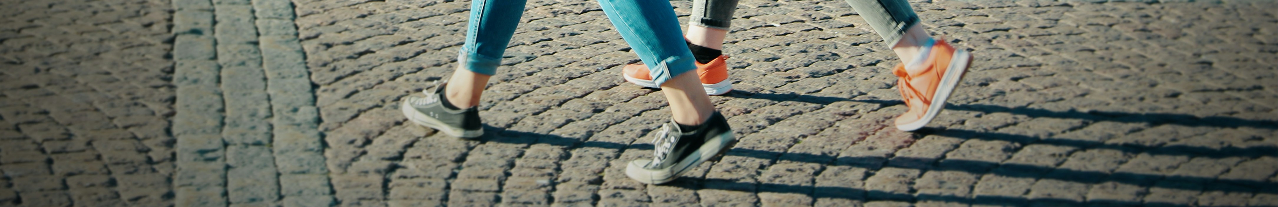 Deux femmes portant des baskets lifestyle marchent côte à côte dans une rue en ville.