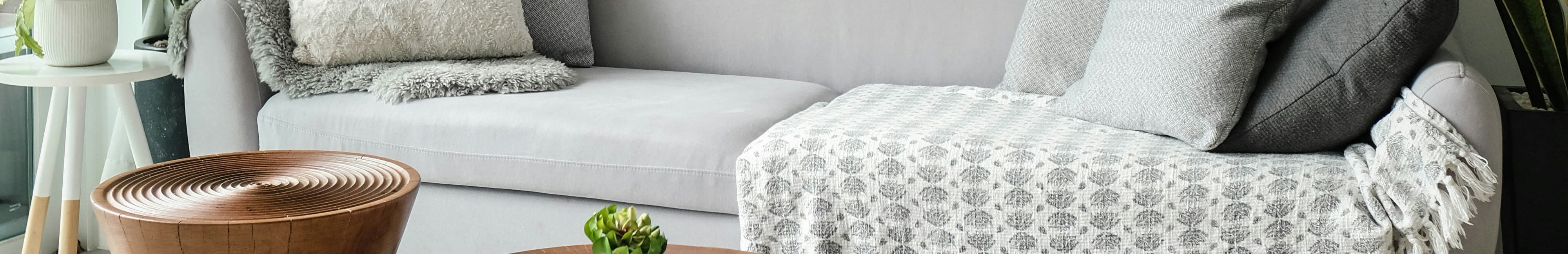 Salon aménagé avec un canapé gris, une table basse et des cadres accrochés au mur.