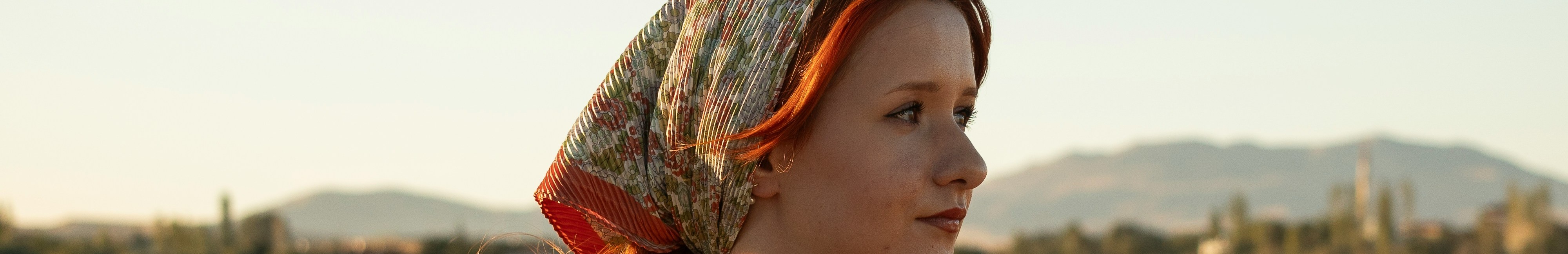 Femme portant un foulard carré sur la tête.