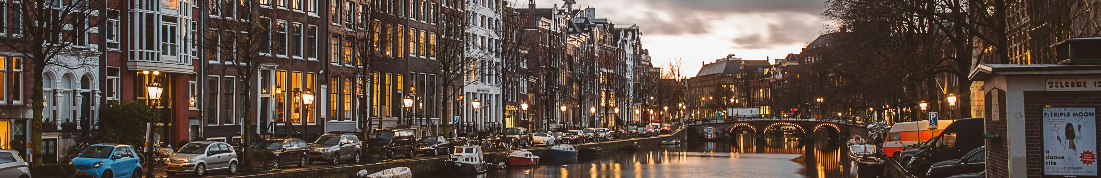 Canal bordés de bâtiments et de voitures garées à Amsterdam.