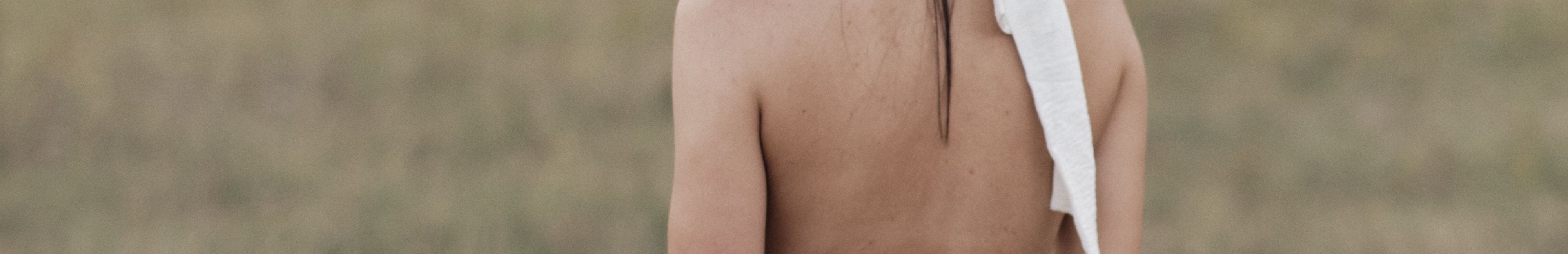 Femme vue de dos, debout dans un champ.