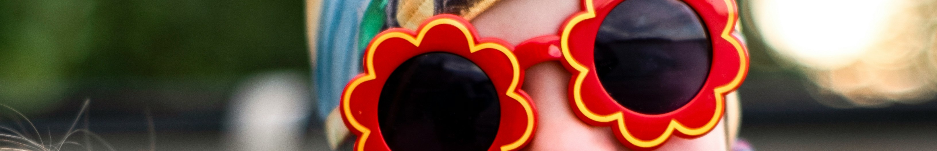 Petite fille portant des lunettes de soleil en forme de fleur.