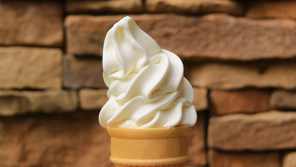 A close-up photo of soft-serve vanilla ice cream on a cone.