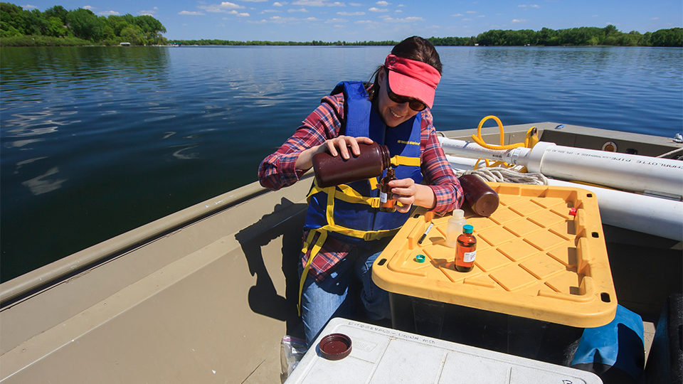 A scientist does an experiment on a boat on a river.
