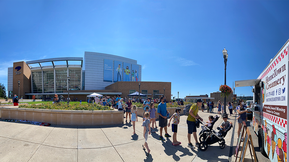 Image of a people in line for a food truck outside of the science museum
