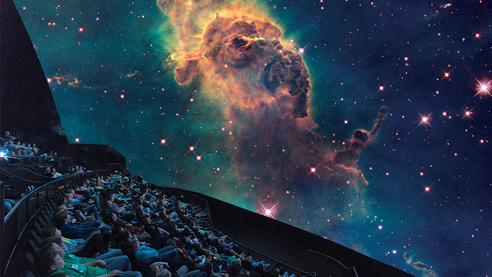 A photo of the Omnitheater with the audience viewing a projection of space.