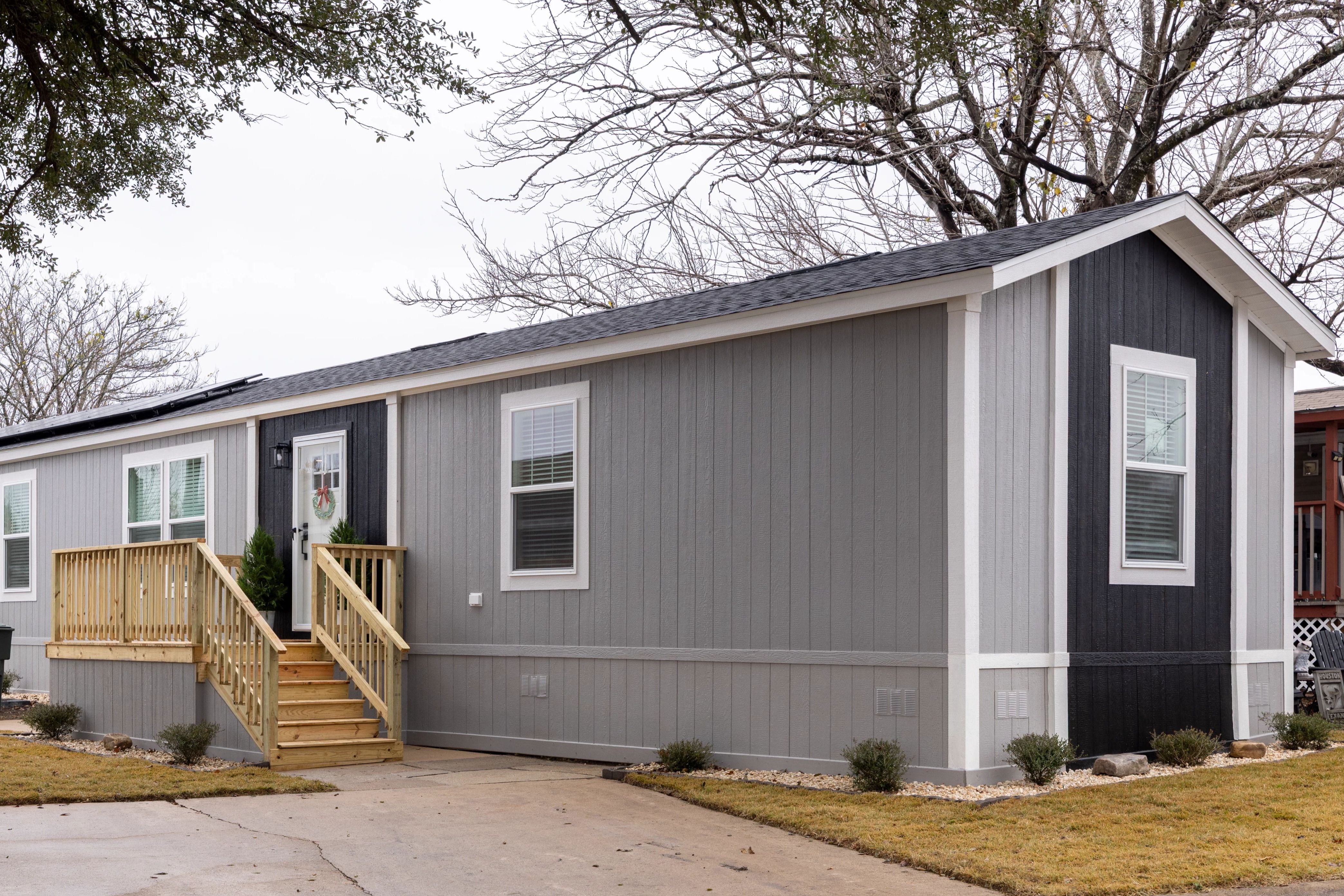 Exterior of a modern manufactured home in a neighborhood, with light and dark gray siding