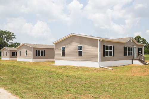 Exterior shot of three brown manufactured homes.