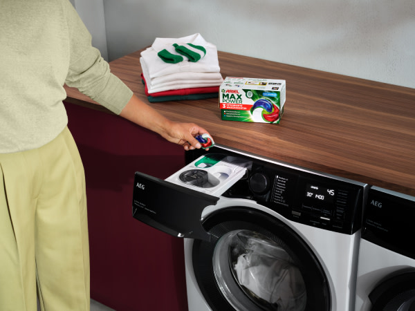 Person, die ARIEL PODS® in einer AEG UniversalDose-Waschmaschine verwendet