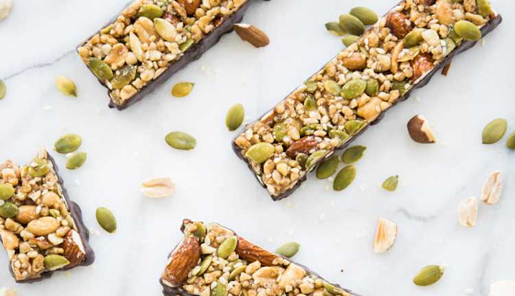 Four nutty bars photographed on a marble backdrop