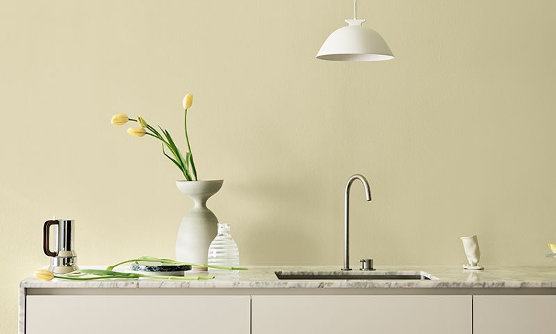 Minimalistisk marmorbenk med gule tulipaner i hvit vase, glasskanne og kran.