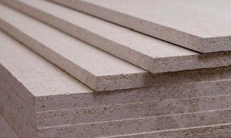 Lysebeige trefiberplater stablet i skrå vinkel, ru overflate.