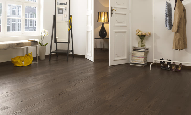 Lyst entrerom med mørk parkett, hvite vegger, gult veske, speil, blomster, klesstativ, åpne dører