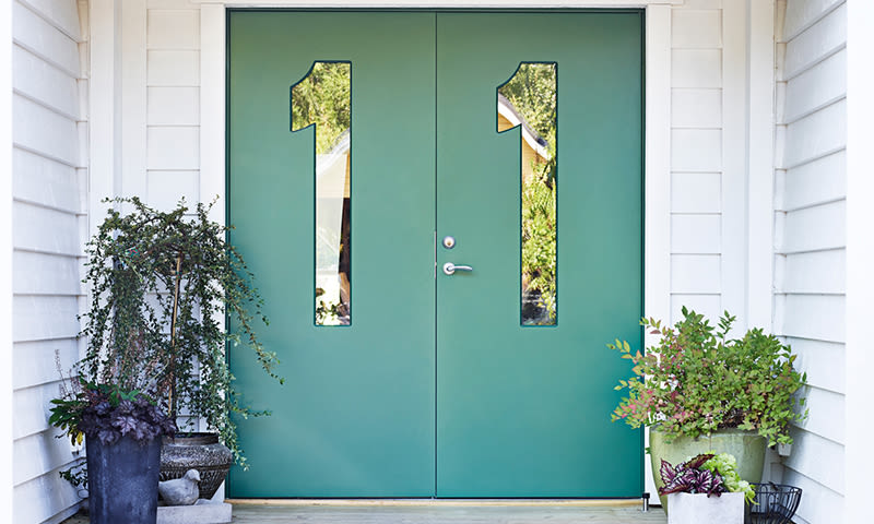 Inngangsparti med grønne dobbeltdører, 1-formede glassvinduer, hvit kledning og potteplanter