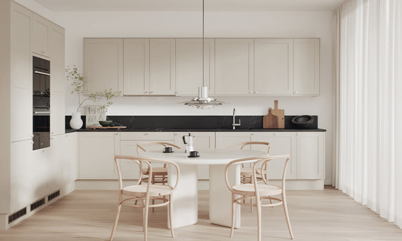 Lyst og luftig kjøkken med beige skap, svart benkeplate, rundt hvitt bord og lyse trestoler.