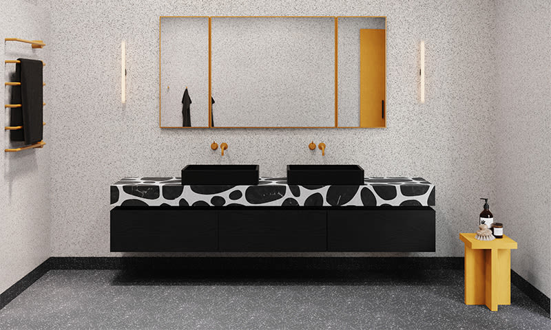 Moderne bad med svart-hvitt terrazzo-benk, to svarte servanter, gullspeil og gul krakk
