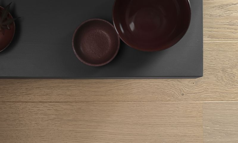 Toppbilde av mørkt brett med røde keramikkboller og liten plante på lyst trebord.