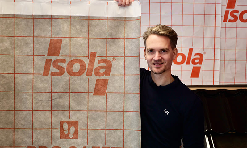 Person holder opp hvit Isola-membran med oransje rutenett og logo.